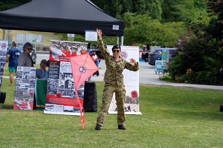 Une personne en uniforme militaire tenant un cerf-volant à l'extérieur.