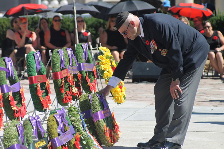 Une personne en uniforme déposant une couronne sur un présentoir