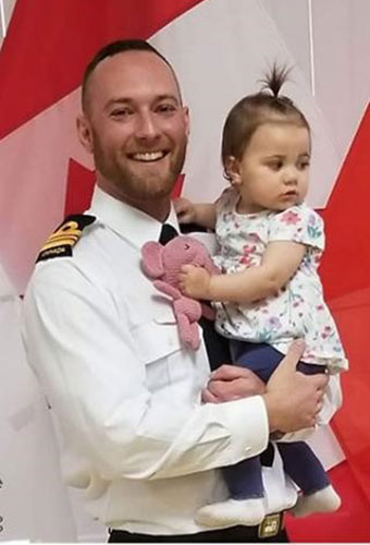 un homme en uniforme tenant un petit enfant