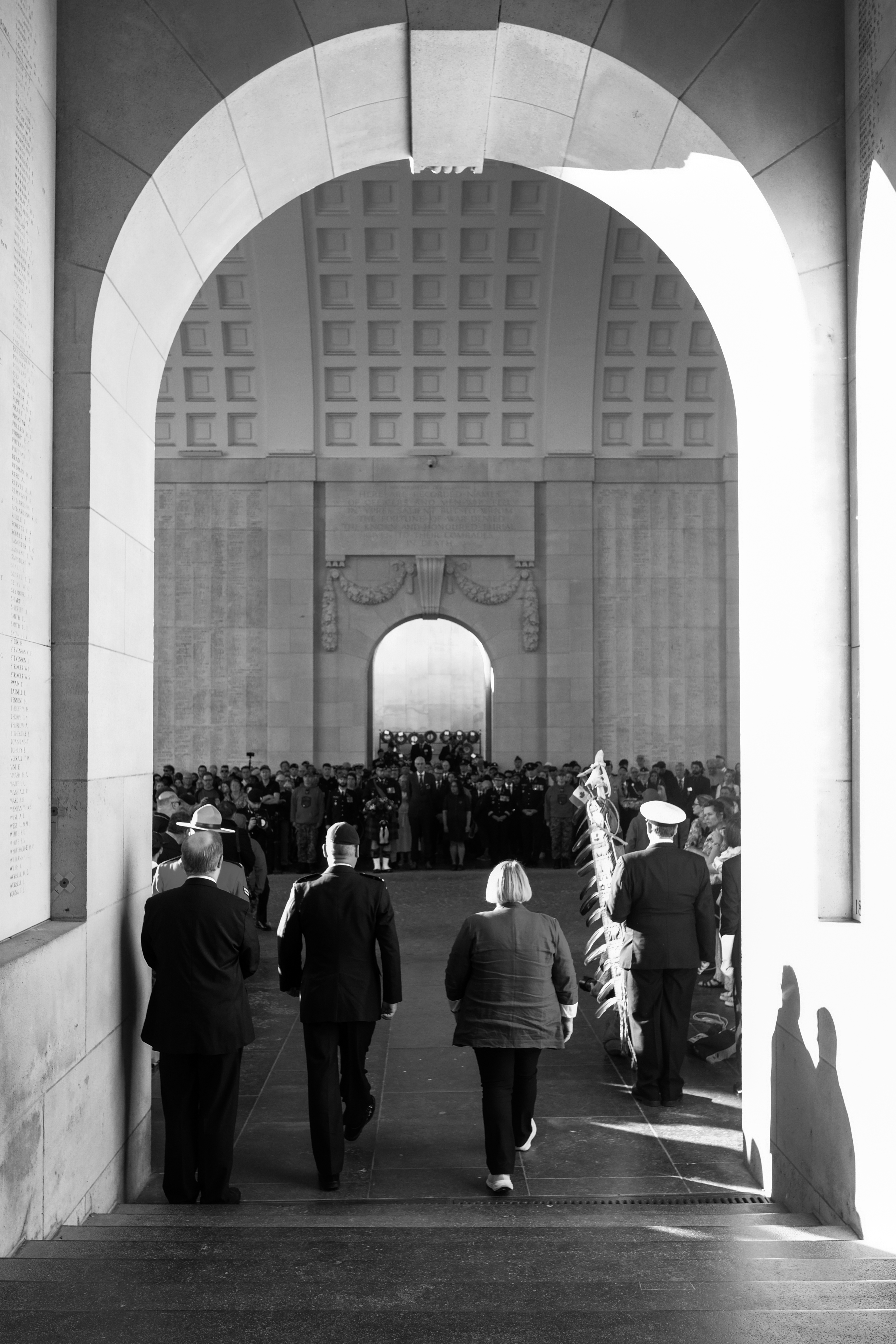 People walk through a large memorial archway.
