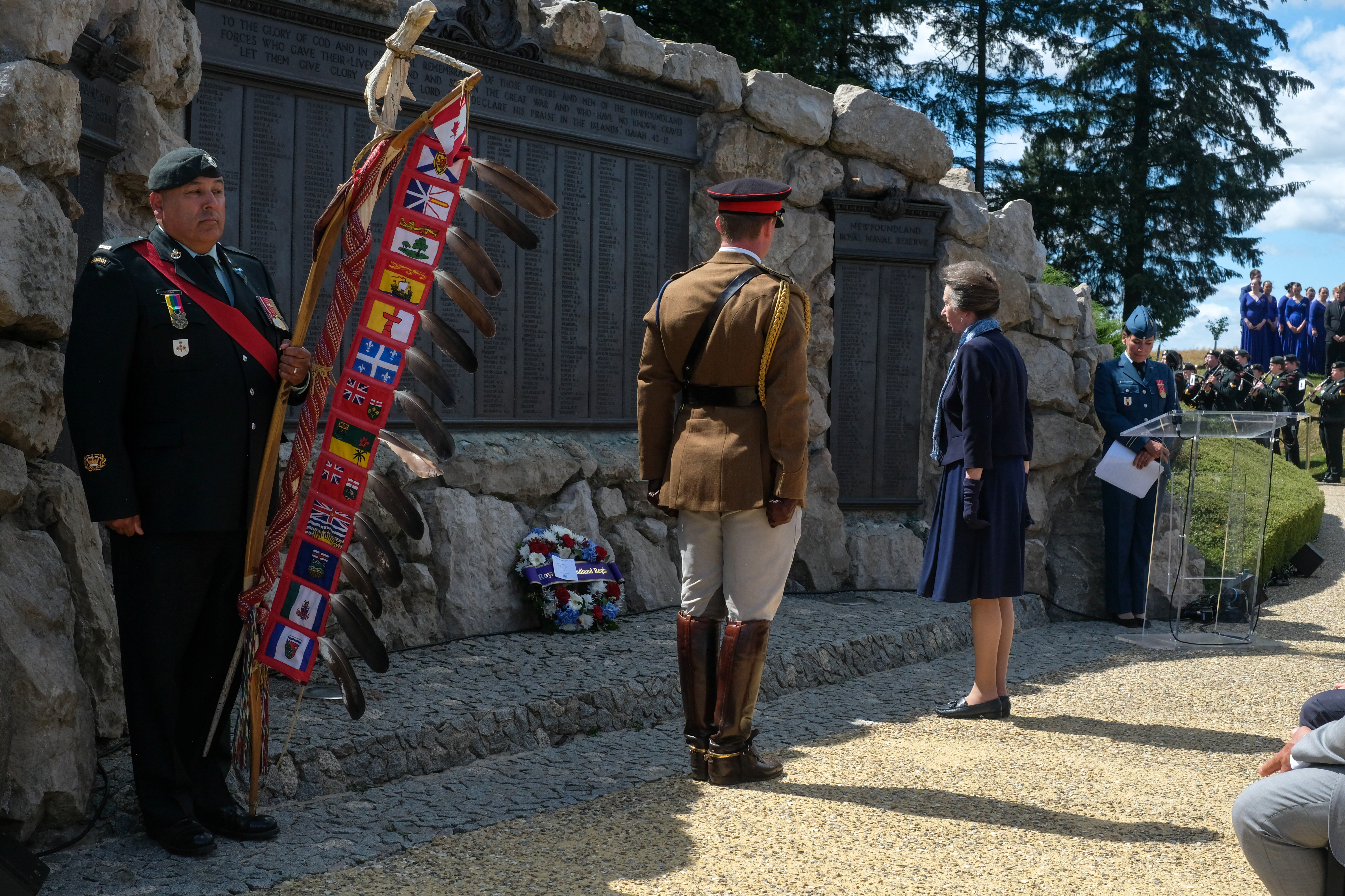 A ceremonial gathering takes place at a stone memorial.