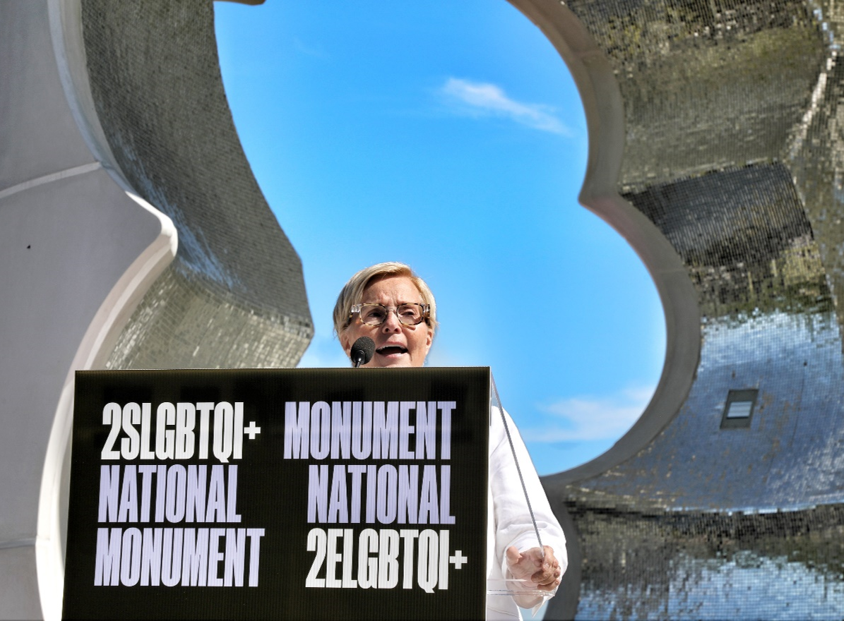 Michelle Douglas speaking at a podium in front of a monument.
