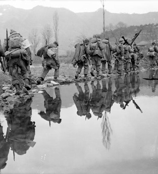A group of soldiers walking along a river