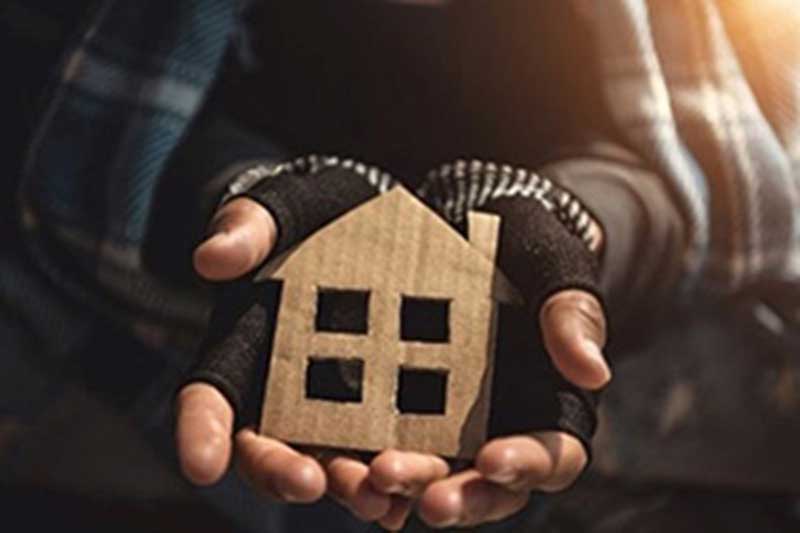 A stock image of a person holding a cardboard cutout of a house