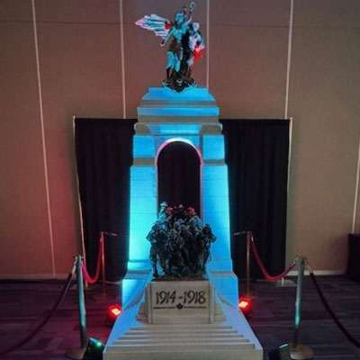 Une maquette du Monument commémoratif de guerre du Canada est exposée à l’intérieur, éclairée de lumières bleues et entourée de cordes.