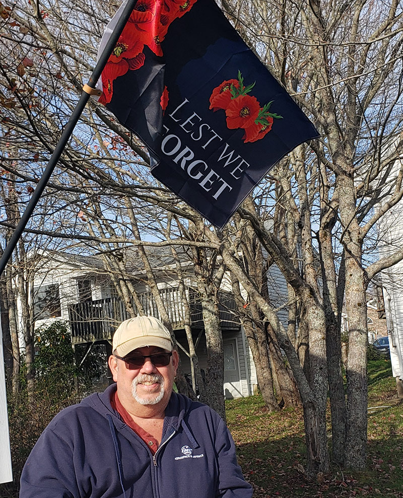 Craig Norman standing in front of a Remembrance Day banner