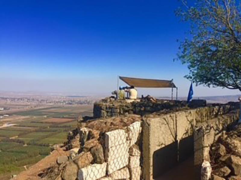 Two UN peacekeepers sit on top of an observation post overlooking the Golan Heights