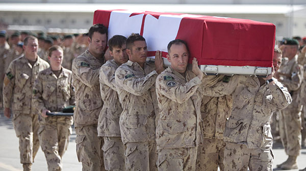 Des soldats en treillis militaire portent le cercueil drapé du drapeau canadien lors d’une cérémonie d’adieu en Afghanistan.