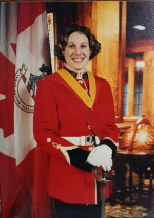 A woman stands smiling for an official military graduation portrait.
